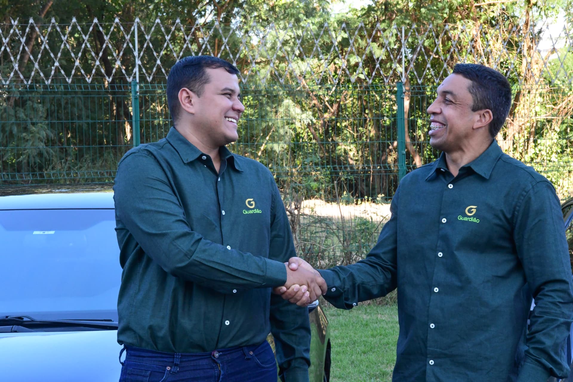 Dois profissionais se cumprimentando ao lado de um veículo